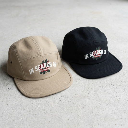 Two caps, one beige and one black, with 'In Search Of' logo on a light gray background